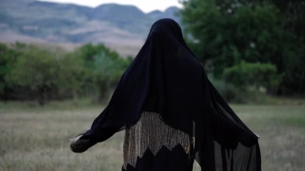 Araberin in Abaya-Kleid und dunklem Schleier läuft über Lichtung — Stockvideo