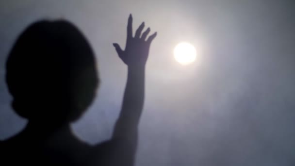 Sylwetka kobiety trzymając rękę do reflektora w mgle — Wideo stockowe