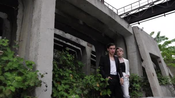 Paar in klassischen Anzügen steht an großer grauer Konstruktion — Stockvideo
