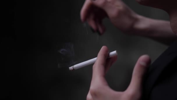 Persona en traje negro sostiene cigarrillo blanco en la mano temblorosa — Vídeos de Stock