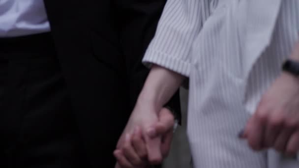 Красива пара в чорно-білих костюмах з'єднує руки — стокове відео