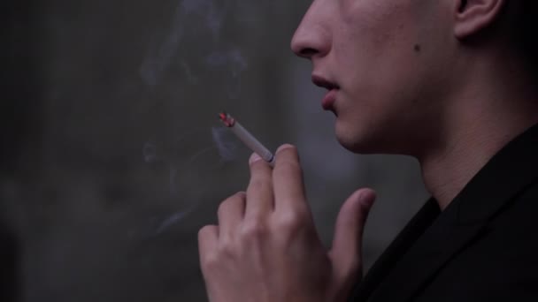 Chlap fouká obláček kouře a drží cigaretu v chvějící se ruce — Stock video