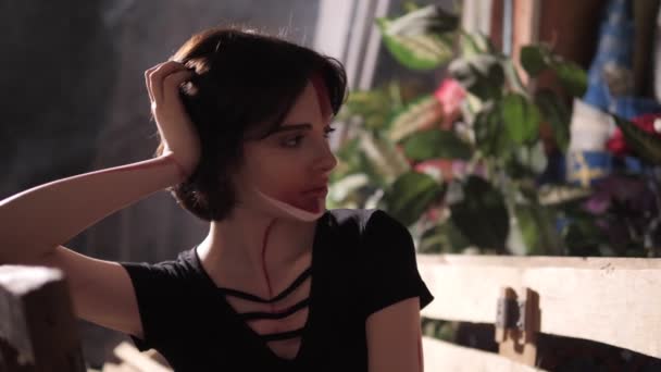 Девушка с макияжем сидит на деревянной скамейке в комнате замедленного движения — стоковое видео