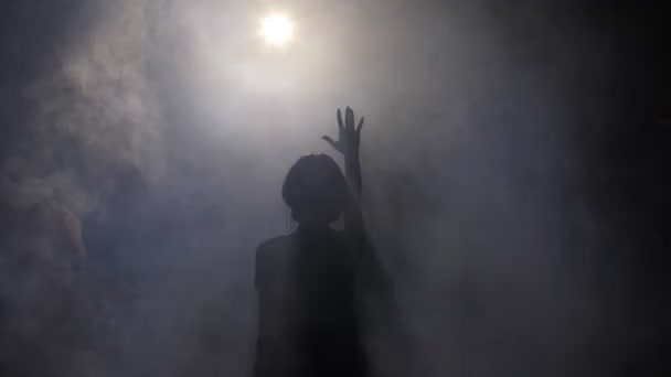 Signora silhouette in piedi con mano sollevata a luce intensa — Video Stock