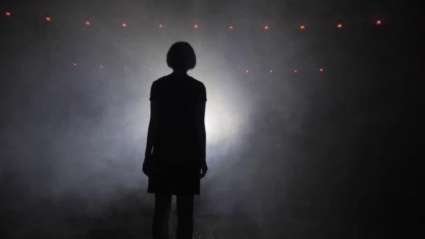 Dark silhouette of lady walking to light in fog slow motion — Stock Video