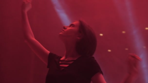 Jonge vrouw dansen het verhogen van de handen bij rood licht Slow Motion — Stockvideo