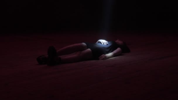 Дама в сеточных колготках лежит под светлым жуком в темном пространстве — стоковое видео