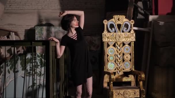 Dame in zwarte jurk dansen rond gouden troon in de kamer — Stockvideo