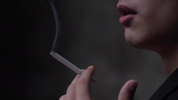 Hombre en traje negro fuma cigarrillo blanco con mano temblorosa — Vídeos de Stock
