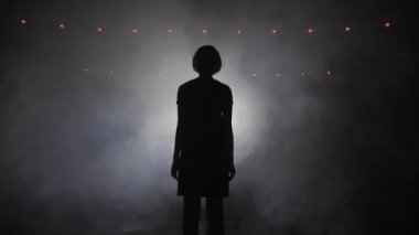 sahnede parlak spot karşı duran kız silueti