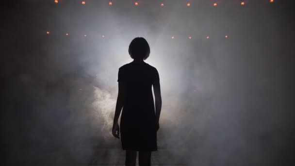 Дівчина силует у вільній сукні розтягує руку до місця на сцені — стокове відео