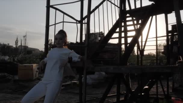 Девушка силуэт опирается на лестницу в порту против захода солнца — стоковое видео