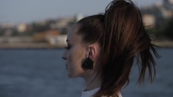 Жінка стоїть наполовину обличчя і свіжий вітерець грає з волоссям — стокове відео