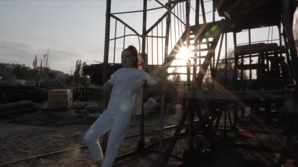Жінка спирається на драбину в морському порту проти блискучого сонця — стокове відео