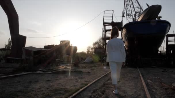 Femme approche navire abandonné contre la lumière du soleil — Video