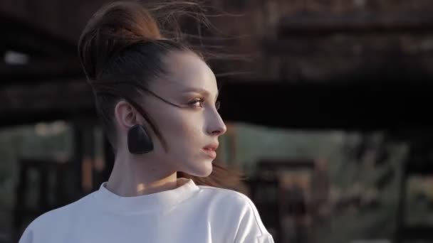 Modèle avec boucles d'oreilles design se tient demi-visage au ralenti — Video