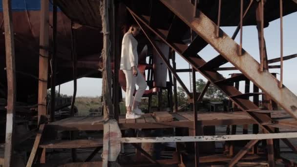 Леди ходит под покинутым кораблем по ясному вечернему небу — стоковое видео