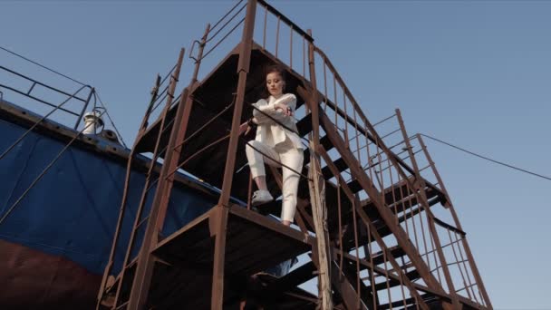 Lady stands on ladder platform of abandoned ship against sky — Stock Video