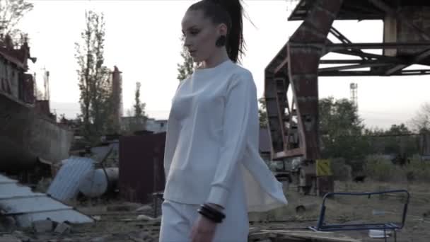 Woman sits down on chair touching face against seaport ruins — Stock Video