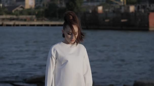 Lány néz félre ellen elmosódott tengeri és távoli város — Stock videók