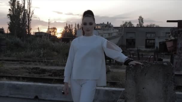Dame houdt zich vast aan betonnen structuur staande tegen zonsondergang — Stockvideo