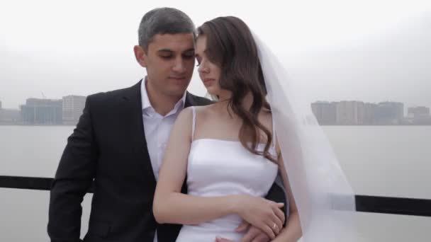 Парень обнимает женщину в открытом плече свадебное платье на террасе — стоковое видео