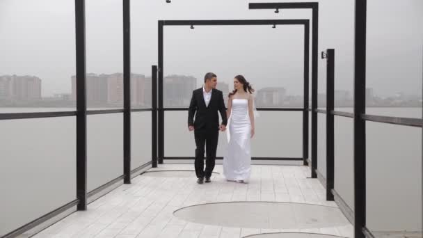 Brud i tight klänning och långa slöja promenader och svänger med brudgummen — Stockvideo