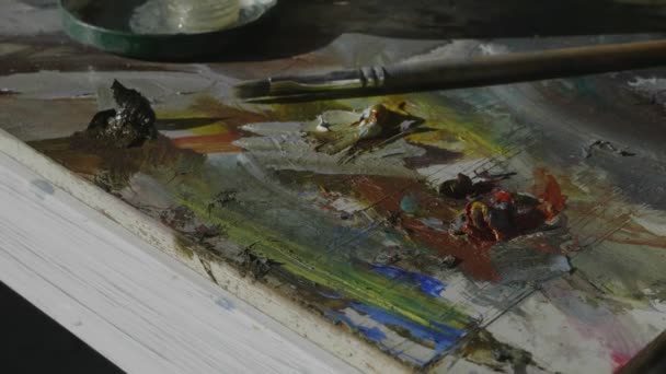 Paleta z jasnymi farbami olejnymi i pędzlem w studiu sztuki lekkiej — Wideo stockowe