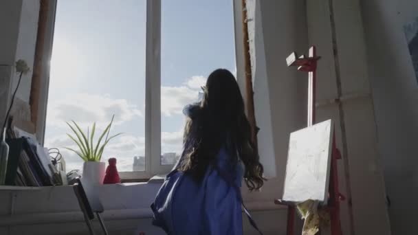 Fille en robe bleue attire soleil et nuages dansant près de la fenêtre — Video