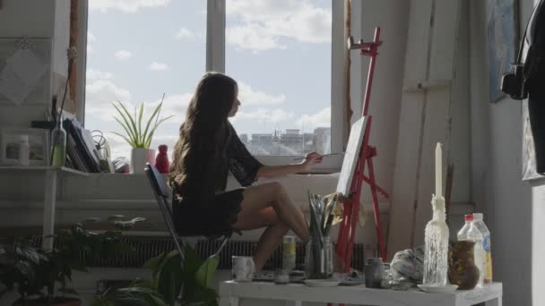 魅力的な女性は窓の筆で絵を描く — ストック動画