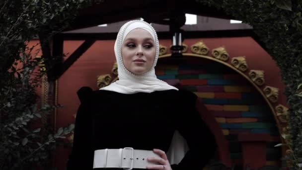 Dáma v elegantním arabském oblečení v blízkosti keřů v restauraci — Stock video