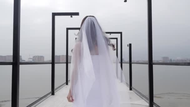 Опытная модель в роскошном свадебном платье с длинной вуали на террасе — стоковое видео
