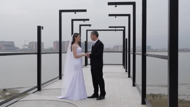 Pár novomanželů stojí na náspu a spojuje ruce — Stock video