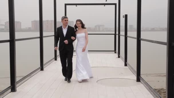 Matrimonio coppia passeggiate lungo argine contro paesaggio urbano — Video Stock