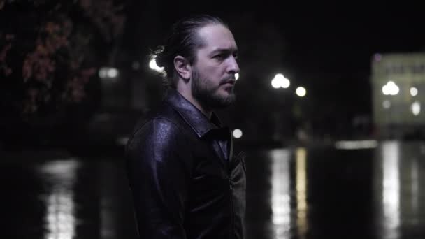 Ensam man i jacka står på ruta vid regn på kvällen — Stockvideo