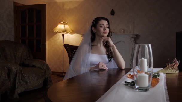 Depressieve dame in trouwjurk met sluier zit aan tafel — Stockvideo