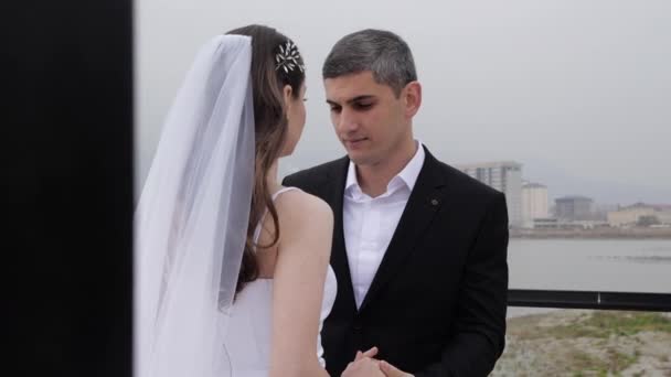 Весільна пара обіймається стоячи на чорних металевих поручнях — стокове відео