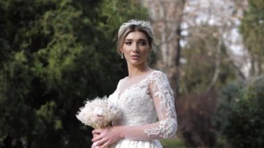 Parkta küçük buketi ve tacı olan muhteşem elbiseli bir kadın.