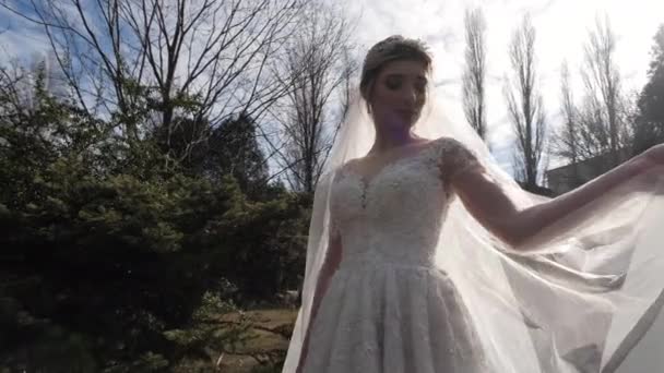 Νύφη σε νυφικό τυλίγει με απαλό πέπλο στο πάρκο — Αρχείο Βίντεο