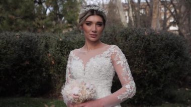 Dantelli kollu, modaya uygun bir gelinlik giymiş hayalperest bir kadın.
