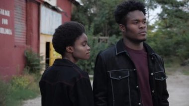 Afro-Amerikalı kadın ve siyah kot giyen adam eski evin yakınında.