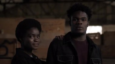 Afro-Amerikalı kadın depoda arkadaşının omzuna yaslanıyor.