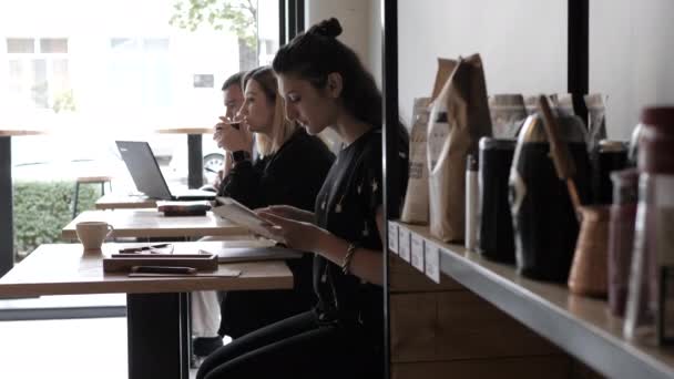 Chica bonita reúne cuadernos de bocetos y lápices en la mesa en la cafetería — Vídeo de stock