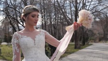 Şık elbiseli gelin ve taç yapay buket taşıyor.