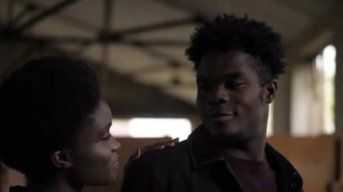 Afro-Amerikalı bir adam eski depoda kız arkadaşına bakıyor.