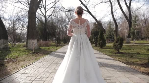 Dame im Brautkleid mit Schnürsenkeln und Schweif spaziert durch Park — Stockvideo