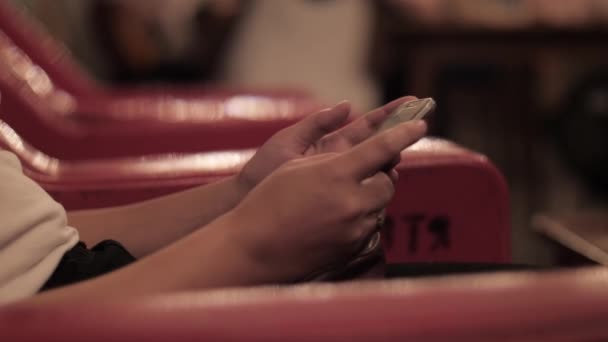Vrouw surft internet met smartphone zitten in rode fauteuil — Stockvideo