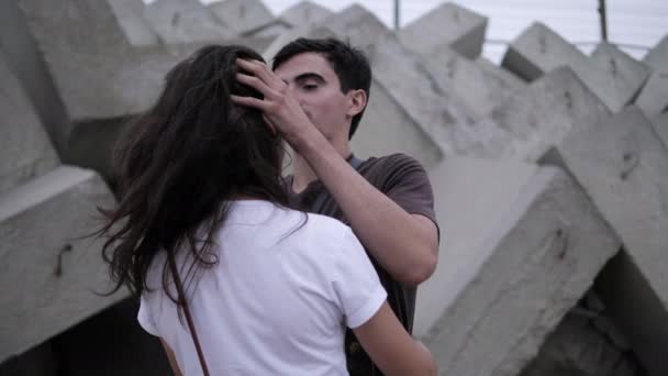 Positieve man en vrouw knuffel in de buurt breakwater op zee strand — Stockvideo