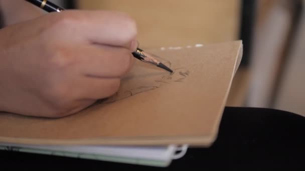 Femme dessine portrait d'homme dans carnet de croquis avec crayon graphite — Video