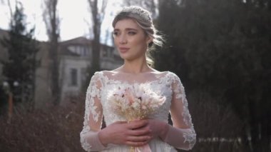 Muhteşem elbiseli neşeli gelin zarif bir buket tutuyor.